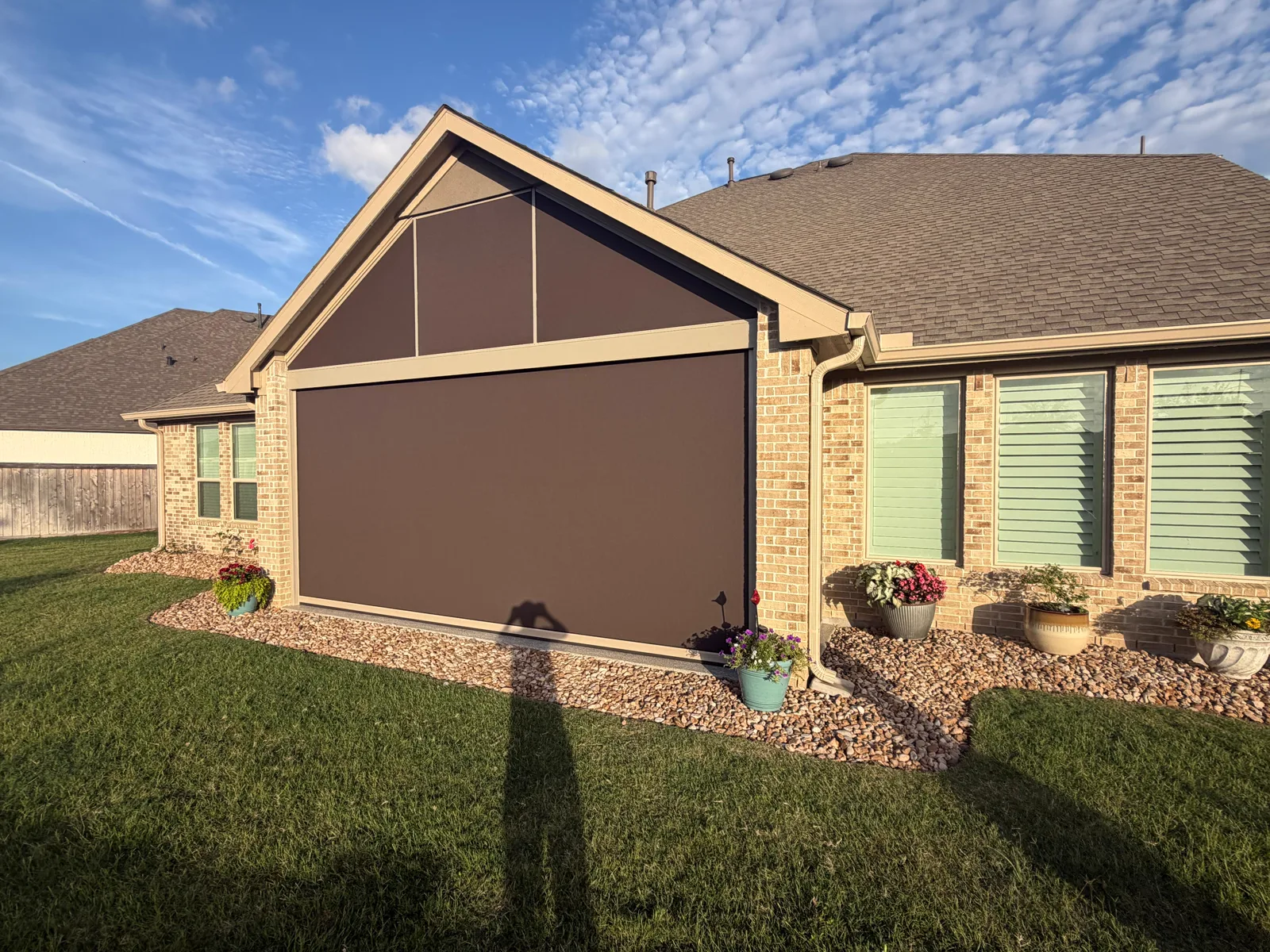 Houston patio fully enclosed by motorized screens, creating a private outdoor retreat beside a landscaped lawn.