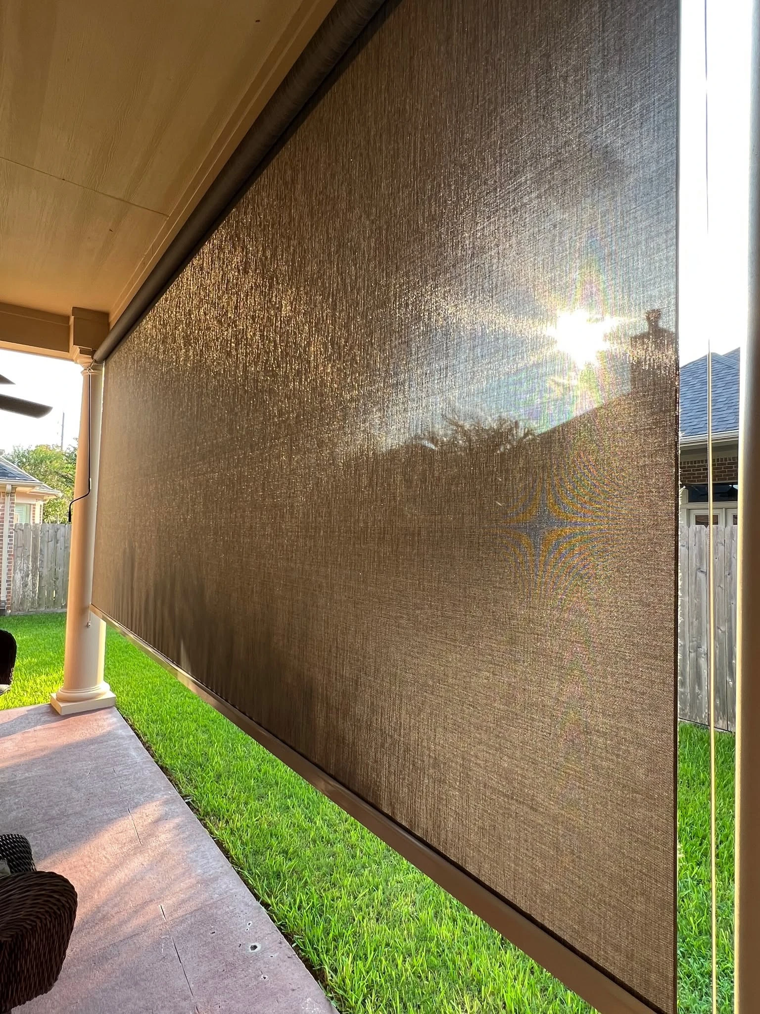Roller patio shade lowering over a Houston outdoor living space